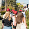 Students with red hats walking next to canal